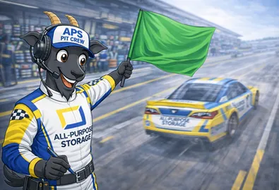 A cartoon goat in a pit crew uniform waves a green flag at a race track as a race car speeds by